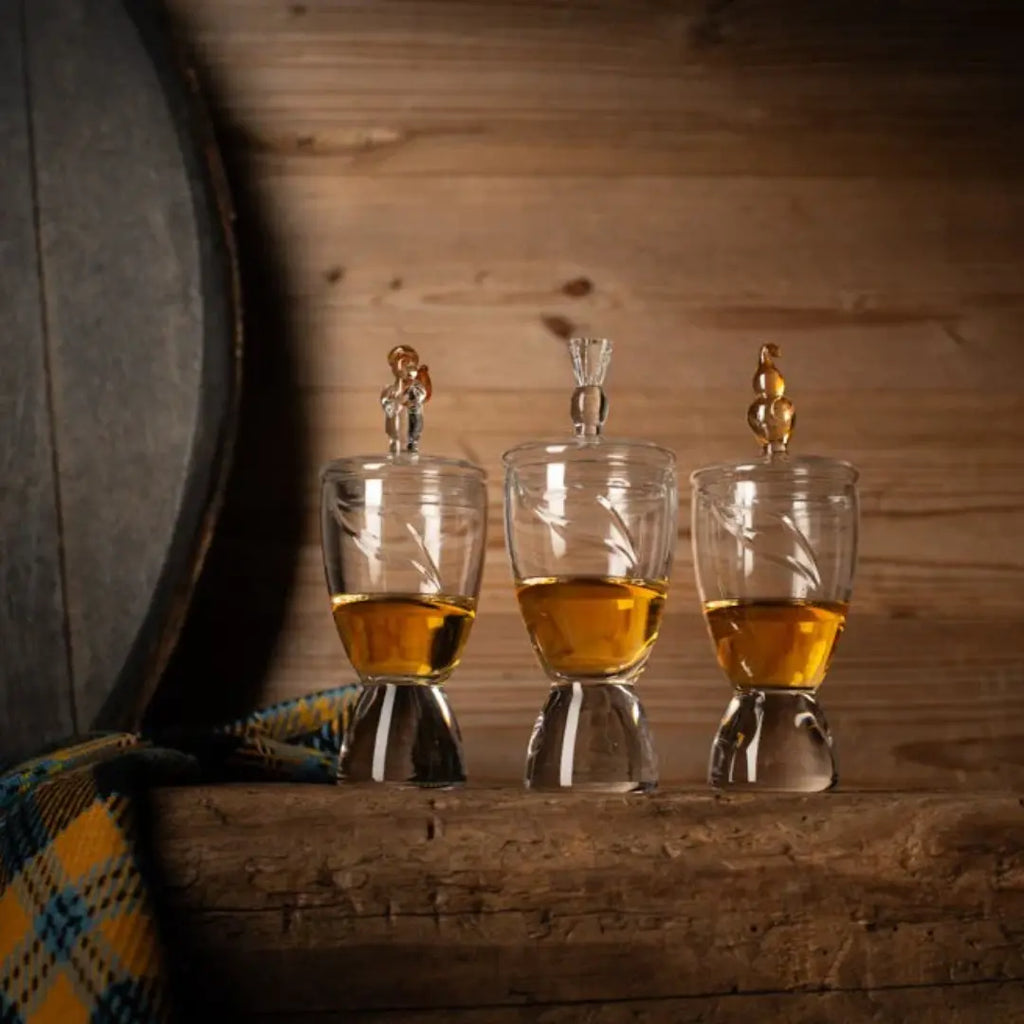 Three glasses of whisky on a wooden surface with a wooden background. with glss lids